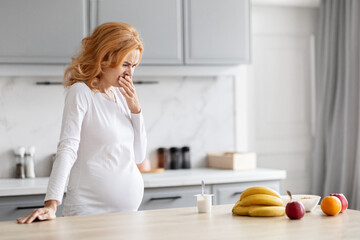 Expectant mother in distress in kitchen, copy space