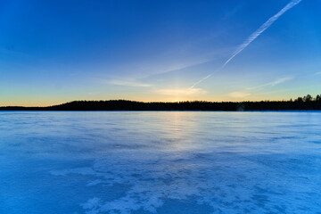 Beautiful winter sunset in small forest lake