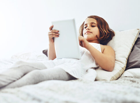 Home, lying and child on tablet in bed for game, relax and streaming cartoon or movies in bedroom. Happy girl, connection and tech in house for learning, education or reading ebook on app online