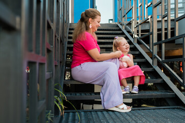 Blonde little girl with cochlear implant playing with her mother outdoor. Hear impairment deaf and health concept. Diversity and inclusion. Copy space