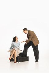 Man in suit gesturing at seated woman on the floor. Couple quarreling, emotionally arguing. Young...