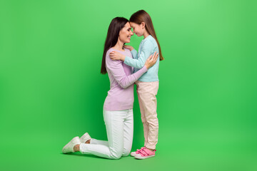 Full body portrait of two people mother daughter hug touch heads isolated on bright green color background