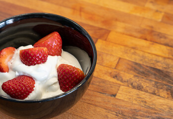 Black bowl with strawberries and yogurt