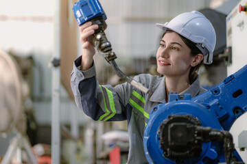 Industrial engineer woman working on robot arm maintenance in futuristic technology factory....