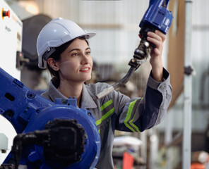 Industrial engineer woman working on robot arm maintenance in futuristic technology factory....