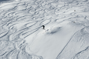 Skier skiing in the Swiss alps off-piste freestyle jumping performing tricks