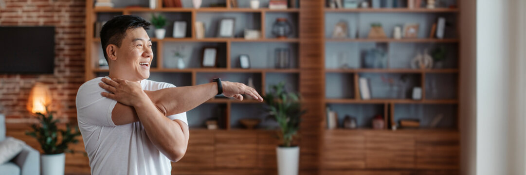 Active asian mature man stretching arm muscles at home - Powered by Adobe