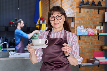 Woman in apron, food service coffee shop worker, small business owner with cup of coffee
