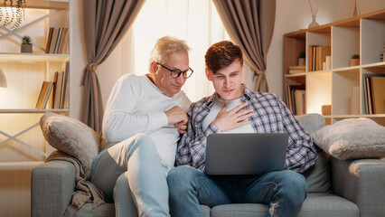 Internet leisure. Family generation. Online research. Happy inspired father and son surfing on laptop together home room interior. - 787231746