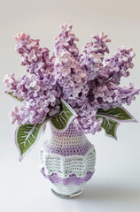 Beautiful crocheted lilac bouquet in an elegant white vase made of crocheted wool, flowers and leaves are crocheted 