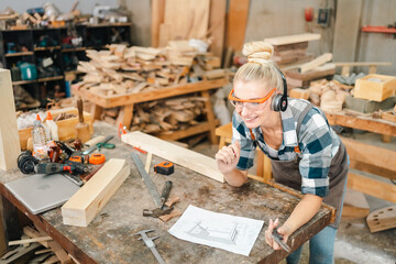 In the carpenter's shop, a professional woman crafts wooden furniture, using tools with skill in...