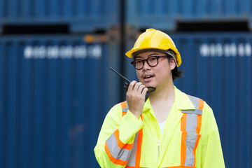 Male container yard worker loading containers box at commercial dock site. Male worker control loading container box from cargo freight ship for import export