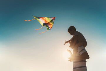 dad and little son 3 years old fly a kite in a field silhouette. Involved Parenting, International...