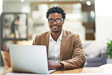 Laptop, portrait and research with business black man in office for administration or project management. Computer, glasses and suit with confident young employee in workplace for online planning
