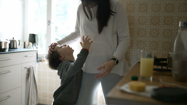 Tender Moment Between Mother and Son - Young Boy Leaning on Mom wanting a hug and embrace, Captured in an genuine, Authentic Family kitchen Setting