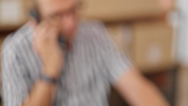 Focused male employee using barcode scanner on packages in a busy warehouse office