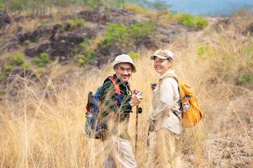 active senior couple hiking together on summer time,they are turn around,smiling and looking at camera,concept of elderly pensioner lifestyle,family relationship,activity,travel,adventure in nature .