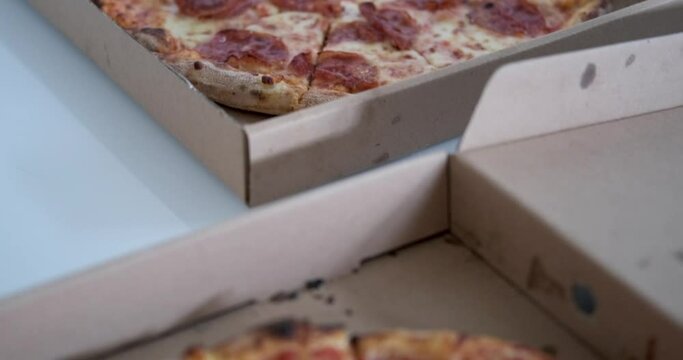 A close-up of two boxes that are on the table containing pepperoni pizza and margherita. Delicious pizza delivered to your home. Crispy crust, stringy cheese and sausage. Fast food concept.