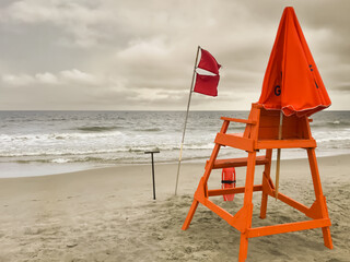 Lifeguard stand and red flags flying on a beach as a storm approaches