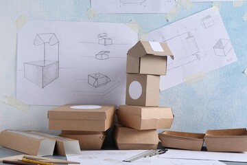 Creating packaging design. Drawings, boxes and stationery on table, closeup