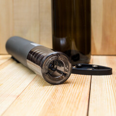 Electric corkscrew, wine bottle and film opener light wood background.