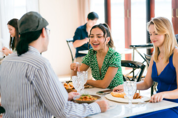 Happy Clients Enjoying Meals and Conversations at the Eatery: A Group of Friends Gathered Indoors, Smiling and Talking Over Lunch and Dinner, Creating Memorable Dining Experiences Together