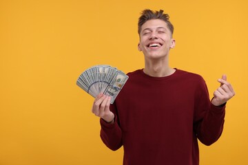 Happy man with dollar banknotes showing money gesture on yellow background. Space for text