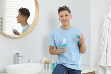 Young man with mouthwash in bathroom. Oral hygiene