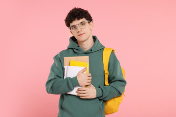 Portrait of student with backpack and notebooks on pink background