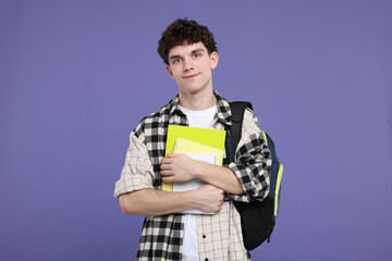 Portrait of student with backpack and notebooks on purple background