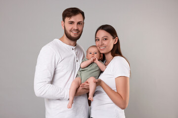 Happy family. Parents with their cute baby on grey background