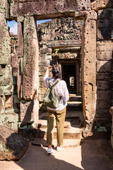 Female tourist looking at ancient Angkor temple in Cambodia