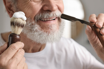 Man shaving mustache with blade in bathroom, closeup