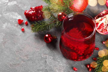 Aromatic Sangria drink in glass, Christmas decor and pomegranate grains on grey textured table,...