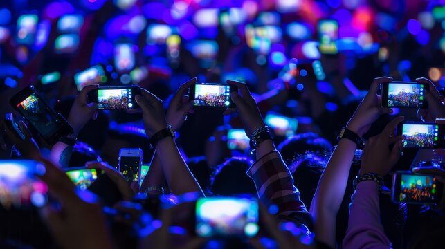 A crowd of people at a concert, raising their cell phones to take pictures. The glowing screens illuminate the scene
