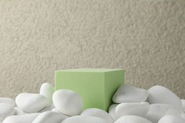Presentation for product. Light green cube podium and white pebbles on blurred background. Space...