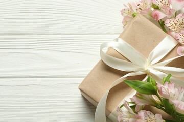 Happy Mother's Day. Beautiful flowers and gift box on white wooden table, flat lay. Space for text