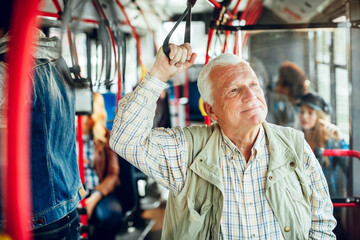 Senior man riding public bus and looking out window