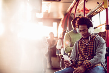 Young man on the bus with smartphone and headphones