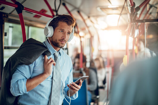 Businessman listening to music on headphones while commuting by bus