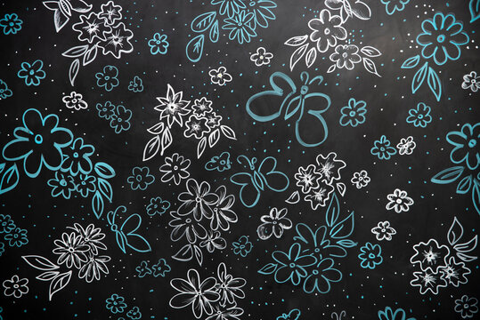 Black background with flowers and butterflies drawn with liquid chalk