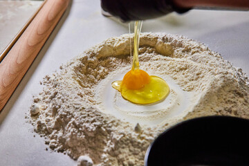 Breaking Egg into Flour for Homemade Pasta, Close-Up View