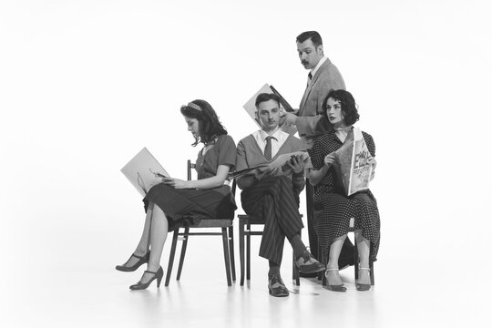 Group of four people, men and women in retro-style clothes sitting on chair and reading newspapers, journals on white background. Monochrome image. Concept of retro and vintage, fashion, news