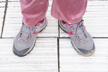 old worn-out shoes, hiking boots on female foot on floor, signs of wear and tear, adding to...