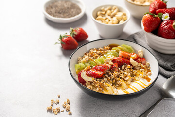 Granola with yogurt, fresh strawberries, kiwi, banana and nuts, seeds. Healthy breakfast. Copy space