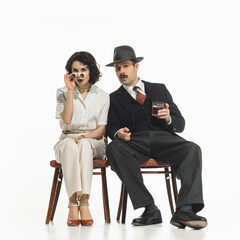 Elegant stylish couple, man and woman in classical suits with binoculars sitting and watching performance. Concept of retro and vintage, fashion, romance, relationship, entertainment
