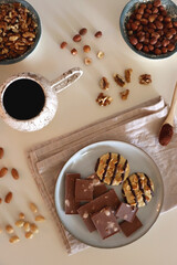 Cup of tea or coffee, cookies, macaroons, chocolate, various nuts and cocoa powder on white background. Top view.