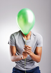 Man, studio and balloon for fun on background, celebration or surprise or retail promotion with decoration item. Male person, playful and sale on isolated on white backdrop with mockup space