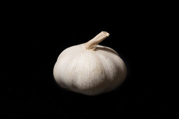 Garlic bulb on a black background. Unpeeled garlic bulb with tenderloin - 787280552