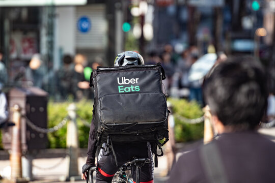 Tokyo, Japan - April   7, 2024 : Uber Eats rider cycling in the street ,delivery service at Tokyo, Japan.